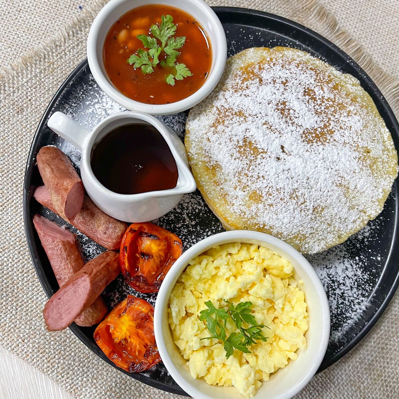 Full American breakfast with pancake, scrambled eggs, baked beans, sausages, grilled tomatoes and syrup