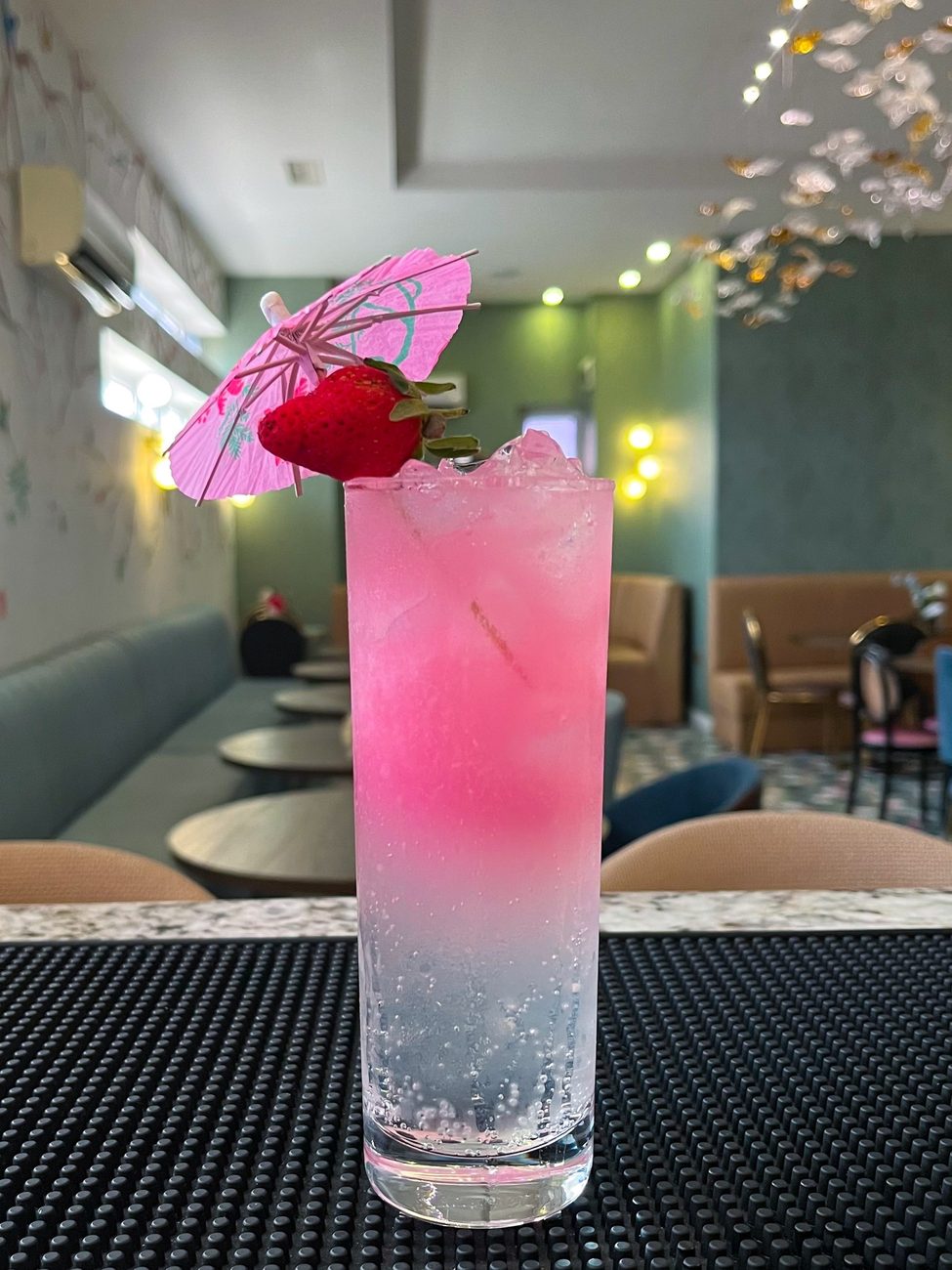 Pink sparkling mocktail with a strawberry and paper umbrella