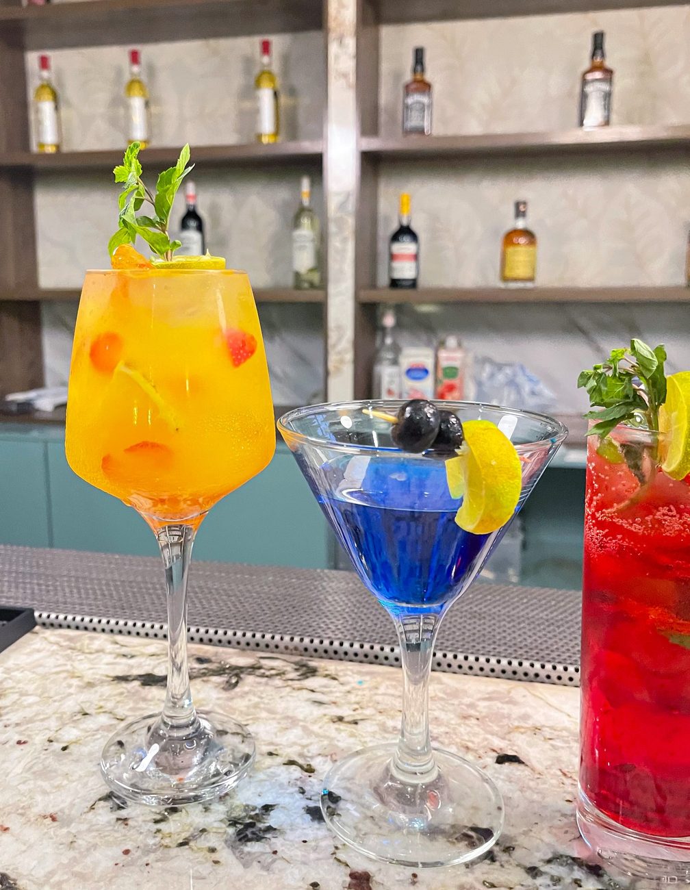 Three cocktails on the marble bar, orange, blue and red
